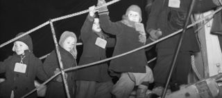 Svartvitt foto av barn som vinkande går på en landgång till ett fartyg