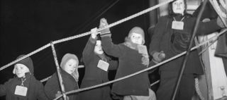 Svartvitt foto av barn som vinkande går på en landgång till ett fartyg