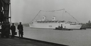 Svartvitt foto av människor som står vid en hamn och tittar på ett stort fartyg i Stockholms inlopp