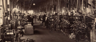 Arbetare står vid maskiner i en fabrikshall