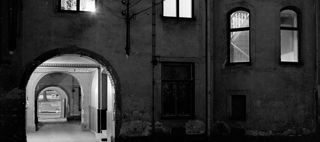 En mörk innergård med upplyst port och fönster