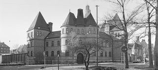 Svartvitt foto av Östermalmsfängelsets fasad, en tegelbyggnad med torn.