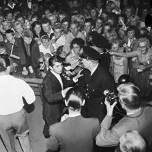Gröna Lund. Kanadensiska rock 'n' roll sångaren Paul Anka uppträder på scenen. I publiken trängs ungdomar med autografblock.