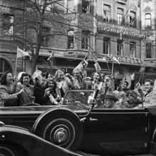 Fredsdagen den 7:e maj 1945.
Glada människor i bilar och på gatan viftar med flaggor på Birger Jarlsgatan.