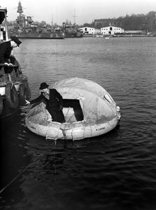 Ladugårdslandsviken. Livflottar demonstreras. Galärvarvet och militärfartyg i bakgrunden