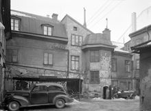 Beridarbansgatan 18. Gården mot väster. En bil, motorcykel och cyklar finns på gården. I fonden portgången och porthuset. I kv. Stigbygeln ligger nu femte höghuset vid Sergels Torg
