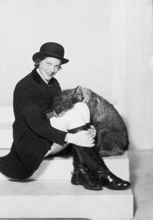 Kvinnande kvinna, hunden bredvid har huvudet i hennes knä.