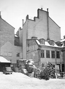 Jakobsbergsgatan 38. Gårdsparti, sydvästra hörnet, med en vedhandel. Här är nuvarande Sveavägen framdragen