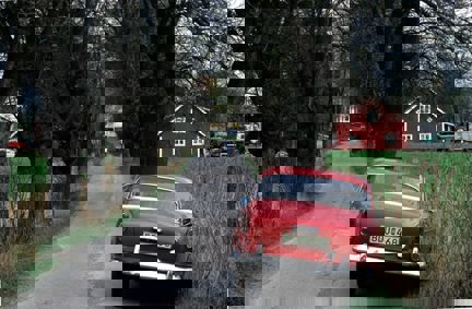 En Volvo står i vägrenen i en asfalterad allé.