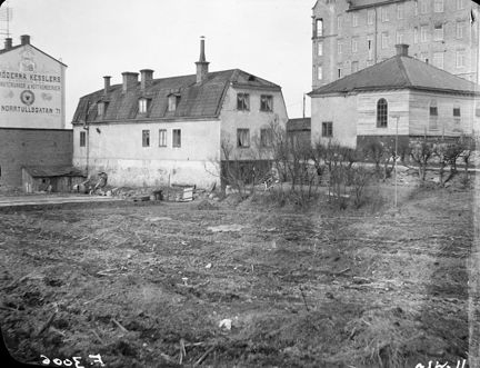 Norrtullsgatan 67. vid en trädgård ligger ett äldre stenhus. i bakgrunden högre stenhus.