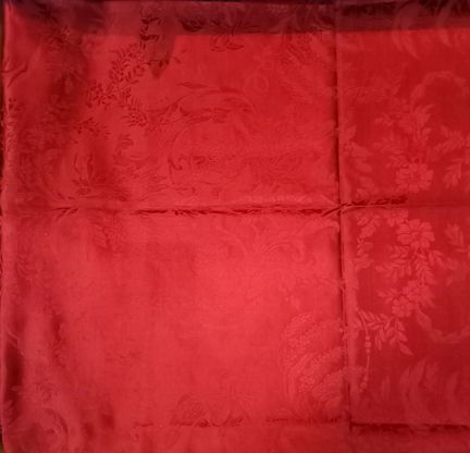 Ett rött, glansigt tyg med mönster av slingrande blommor och ormbunkar av olika sorter