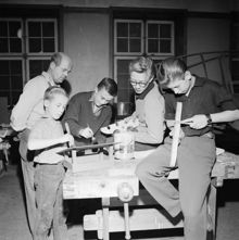 Sadelmakare Åfeldt övervakar julklappstillverkning.Barnen är från vänster Hans och Lennart Åfeldt som målar en fågelholk. Yngve Karlssson och Christer Jernström gör var sin julstake.