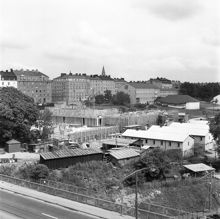 Östgötagatan 80. Folksamhuset byggs. Vy från Skansbron mot Bohusgatan, Stadens trädgård och Högre allmänna läroverket för flickor å Södermalm (Södra flickläroverket)