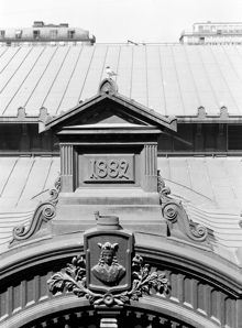 Hötorgshallen före rivningen 1954. Byggnadsdetaljer vid taket med årtalet 1882 då saluhallen byggdes och vapensköld med St. Erik. En skrattmås ser ut över torget
