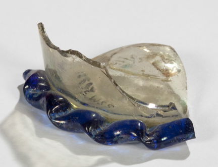 Medeltida glasfragment av dryckesglas, del av botten i genomskinligt glas, kanten är vågig och i blått glas. Fotograferat mot en ljus bakgrund.