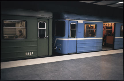 Ett tunnelbanetåg står still vid perrongen i slutet på 1970-talet. Tåget har blå och gröna vagnar. 